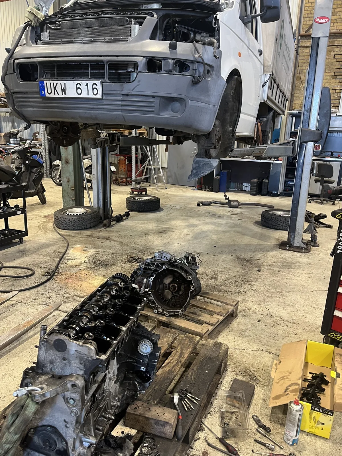 Demonterad motor och fordon på lyft i verkstaden
