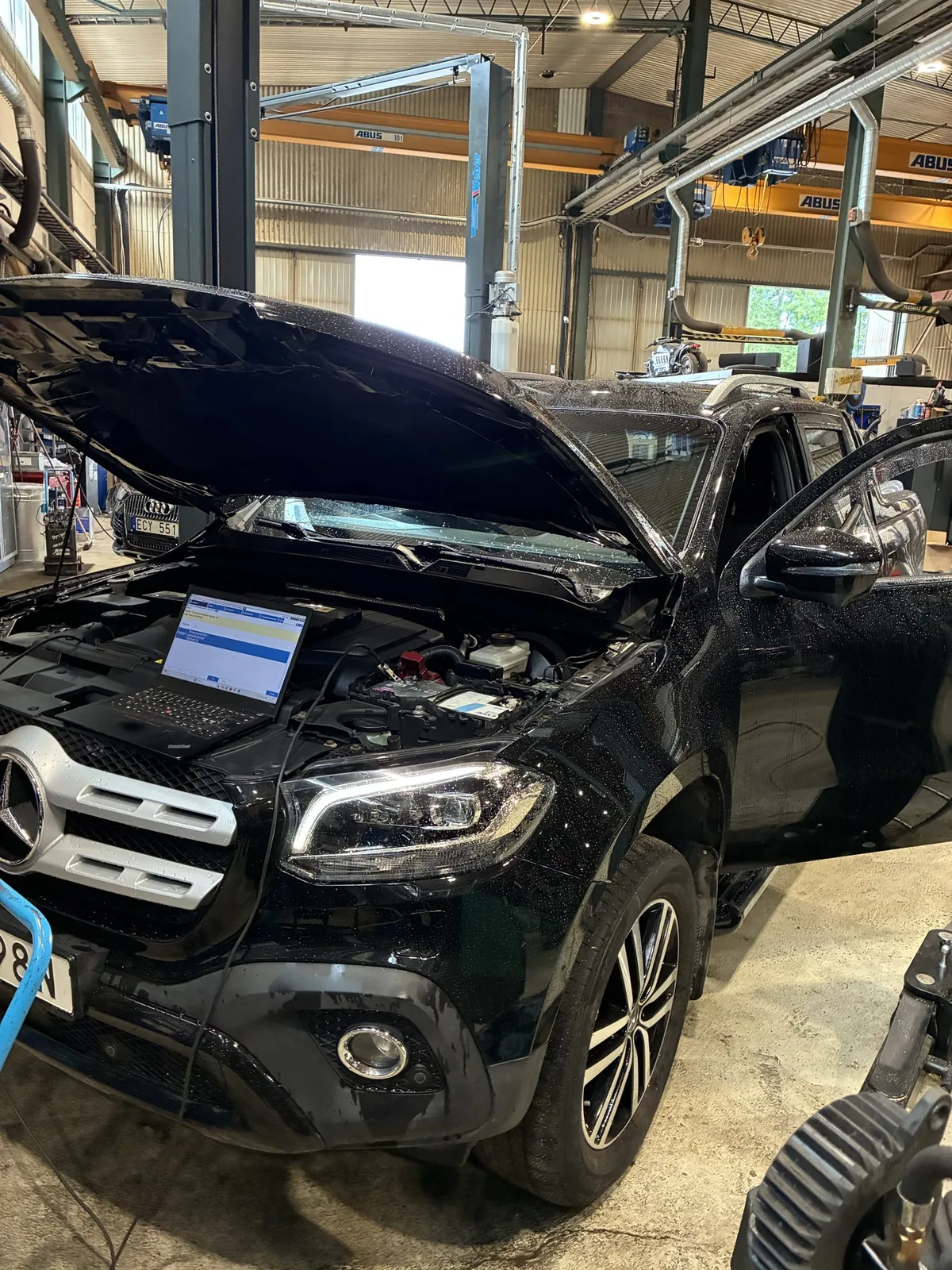 Svart Mercedes med öppen motorhuv i verkstaden